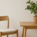 Minimalistische Einrichtung mit Holzstuhl, Tisch, Pflanze und Kerze – Symbol für Minimalismus im Alltag